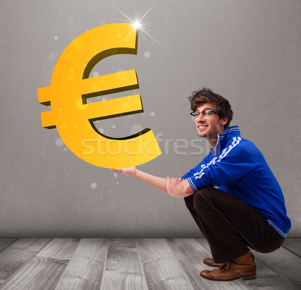 Good-looking boy holding a big 3d gold euro sign Stock photo © ra2studio