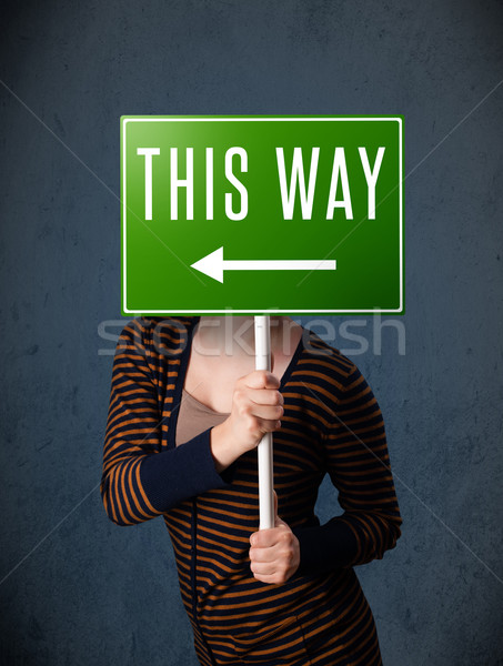 Young woman holding a direction sign Stock photo © ra2studio