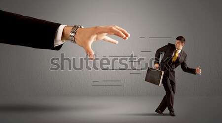 Businessman running away from a huge hand Stock photo © ra2studio