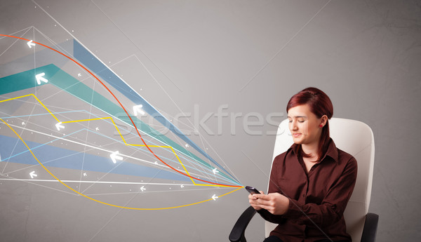 Stock photo: pretty young lady standing and holding a phone with colorful abstract lines and arrows