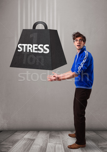 Handsome boy holding one ton of stress weight Stock photo © ra2studio