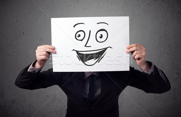 Businessman holding a cardboard with smiley face on it in front  Stock photo © ra2studio