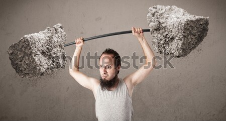 Stock photo: skinny guy lifting large rock stone weights