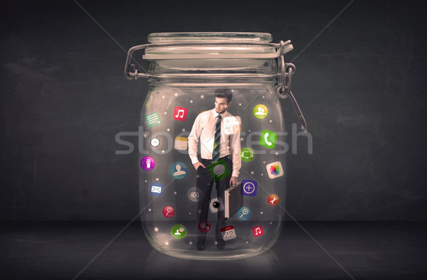 Businessman captured in a glass jar with colourful app icons con Stock photo © ra2studio