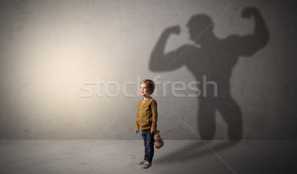 Muscleman shadow behind waggish little boy Stock photo © ra2studio