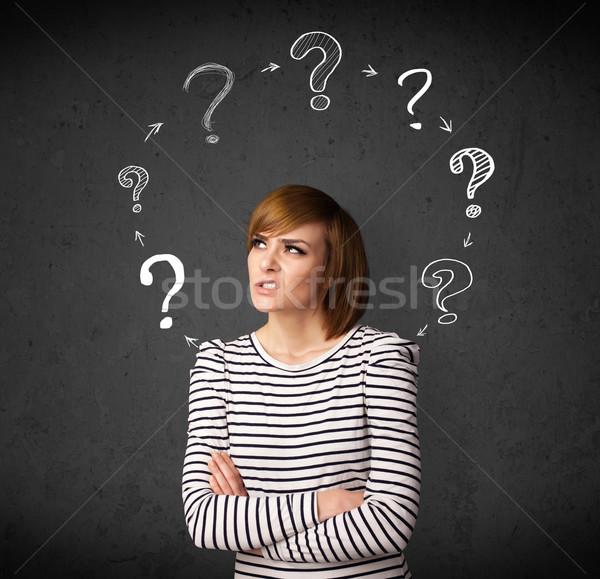 Stock photo: Young woman thinking with question mark circulation around her h