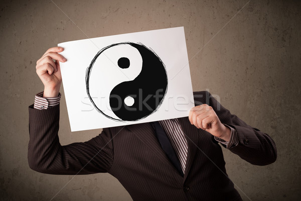 Businessman holding a paper with a yin-yang on it in front of hi Stock photo © ra2studio