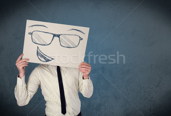 Businessman holding a paper with smiley face in front of his hea Stock photo © ra2studio