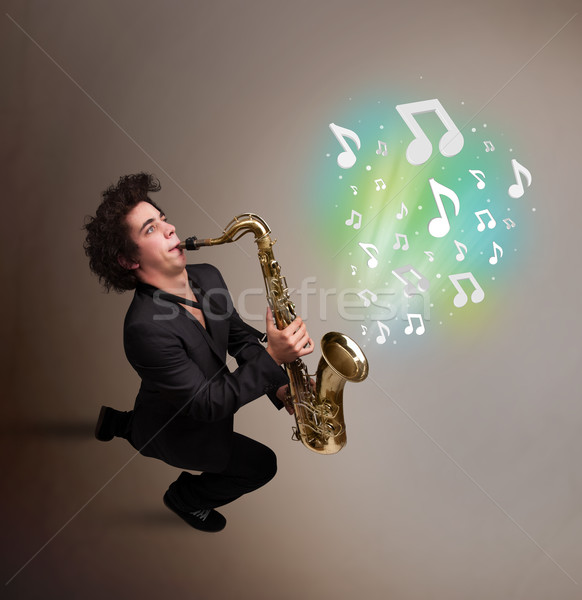 Young musician playing on saxophone while musical notes explodin Stock photo © ra2studio