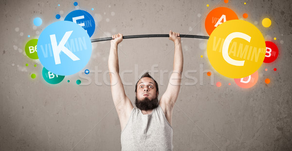 Stock photo: skinny guy lifting colorful vitamin weights