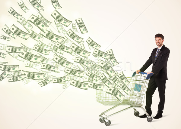 Businessman with shopping cart with dollar bills Stock photo © ra2studio