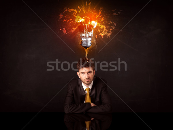 Businessman sitting under a blowing idea bulb Stock photo © ra2studio