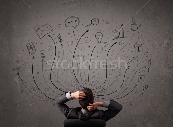 Young businessman sitting and deciding in front of a chalkboard with sketched arrows and signs in di Stock photo © ra2studio