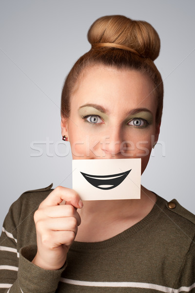 Happy pretty woman holding card with funny smiley Stock photo © ra2studio