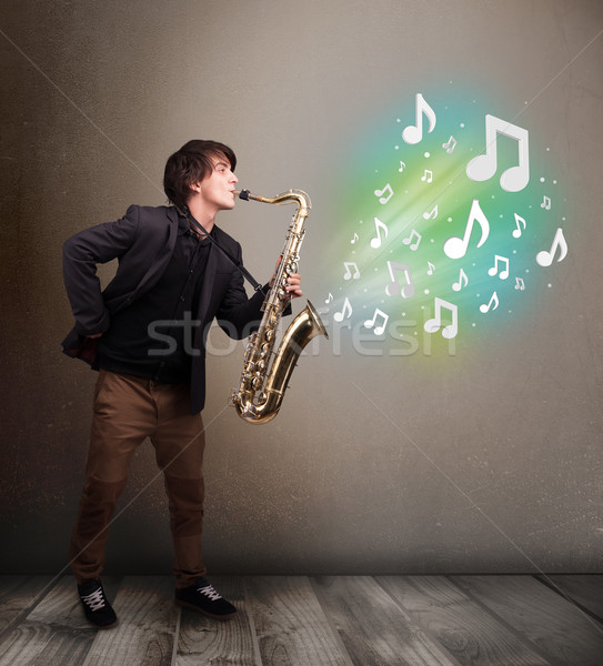 Young musician playing on saxophone while musical notes explodin Stock photo © ra2studio