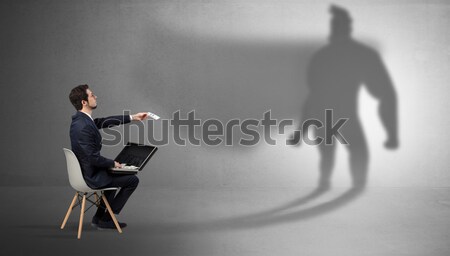 Businessman staying and offering stuffs to a superhero shadow Stock photo © ra2studio