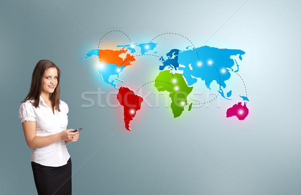 Young woman holding a phone and presenting colorful world map Stock photo © ra2studio