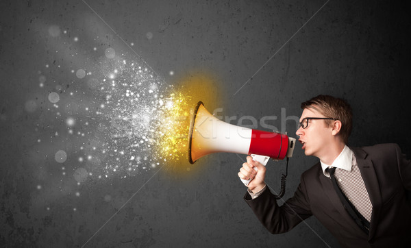 Stock photo: Guy shouting into megaphone and glowing energy particles explode