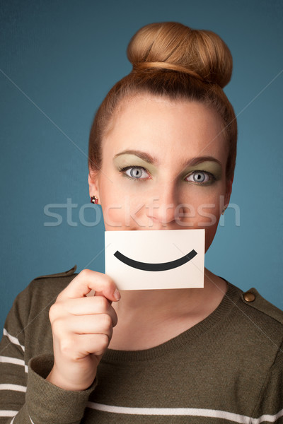 Happy pretty woman holding card with funny smiley Stock photo © ra2studio