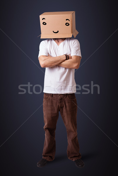 Young man gesturing with a cardboard box on his head with questi Stock photo © ra2studio