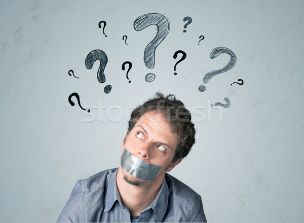 Young man with glued mouth and question mark symbols Stock photo © ra2studio