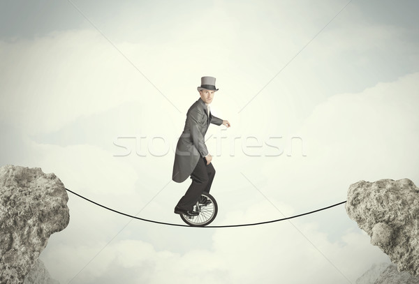 Brave business man riding an mono cycle between cliffs Stock photo © ra2studio