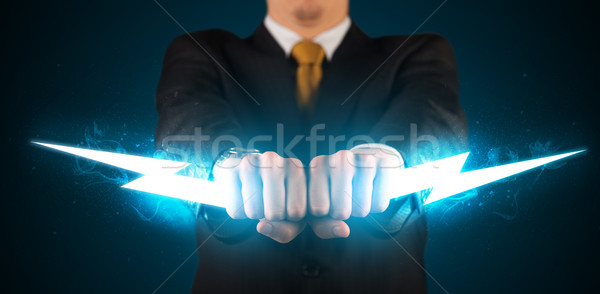 Business man holding glowing lightning bolt in his hands Stock photo © ra2studio