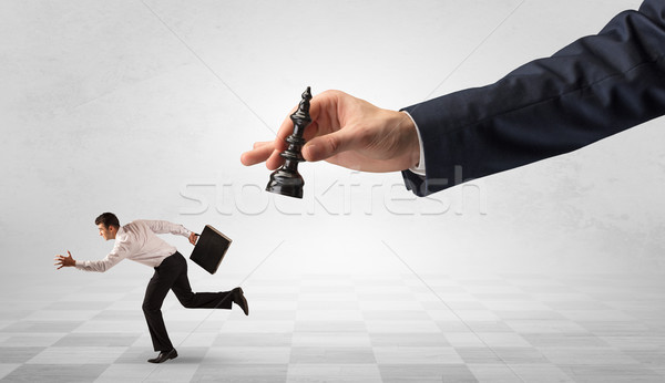 Stock photo: Small businessman running away from big hand with chessman concept