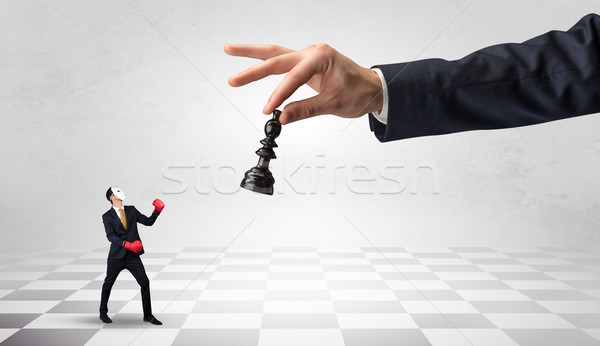 Businessman fighting against big chessman on a big hand Stock photo © ra2studio