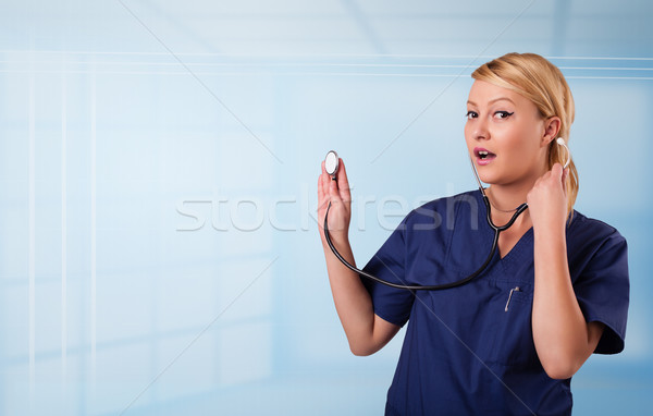 Pretty young nurse in hospital listening to empty copy space with sthetoscope Stock photo © ra2studio
