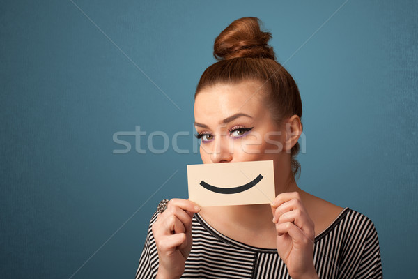 Happy pretty woman holding card with funny smiley Stock photo © ra2studio