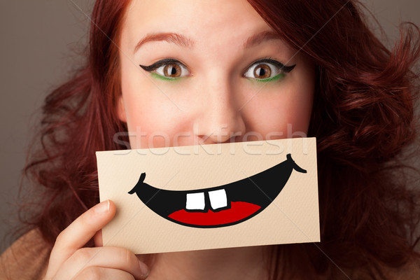 Happy pretty woman holding card with funny smiley Stock photo © ra2studio