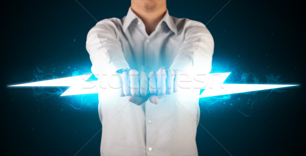 Business man holding glowing lightning bolt in his hands Stock photo © ra2studio