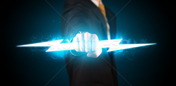 Business man holding glowing lightning bolt in his hands Stock photo © ra2studio