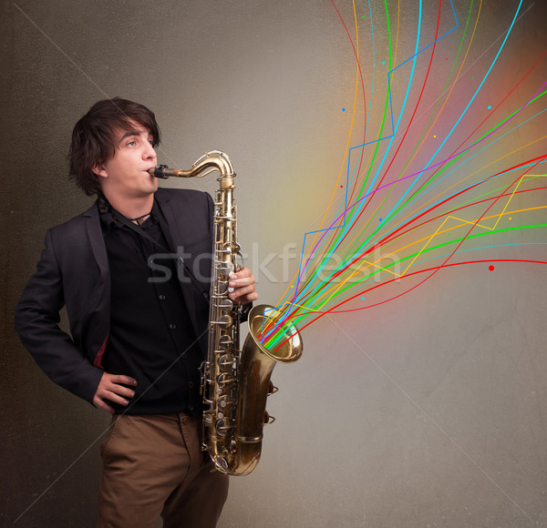 Stock photo: Attractive musician playing on saxophone while colorful abstract