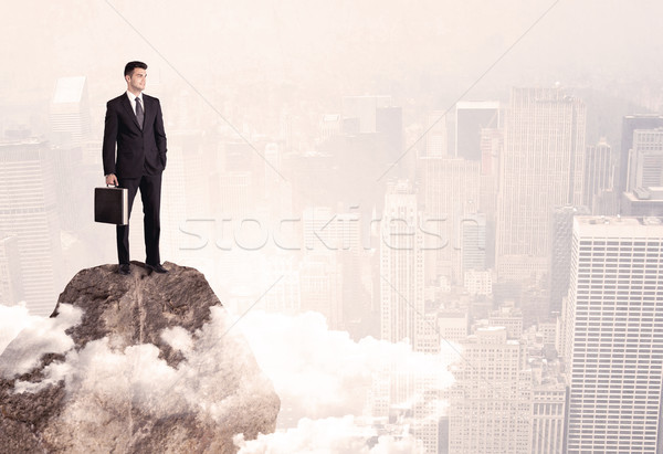 Happy businessman standing on stone top Stock photo © ra2studio