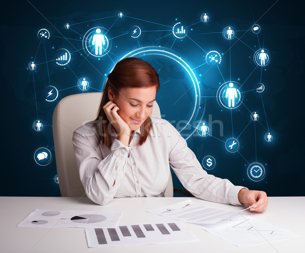 Businesswoman sitting at desk with social network icons Stock photo © ra2studio