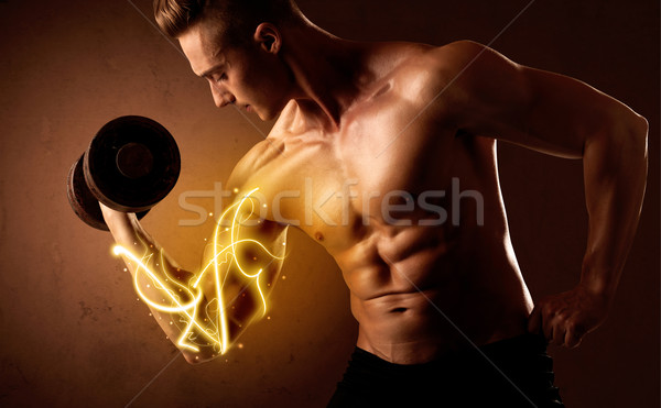 Stock photo: Muscular body builder lifting weight with energy lights on bicep