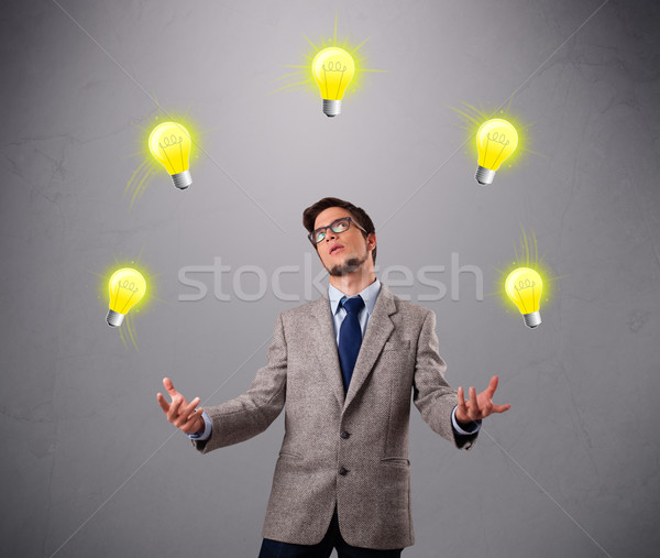 young man standing and juggling with light bulbs Stock photo © ra2studio