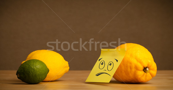 Lemon with sticky post-it note looking sadly at citrus fruits Stock photo © ra2studio