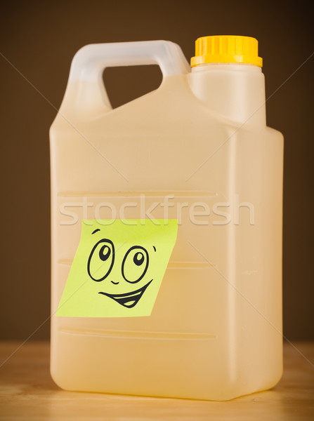 Stock photo: Post-it note with smiley face sticked on gallon