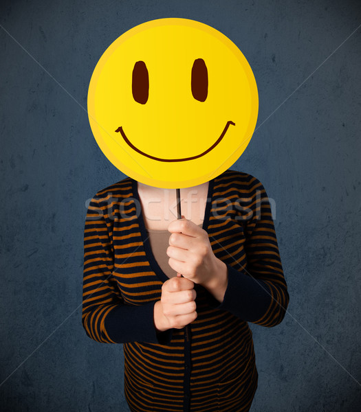 Young woman holding a smiley face emoticon Stock photo © ra2studio