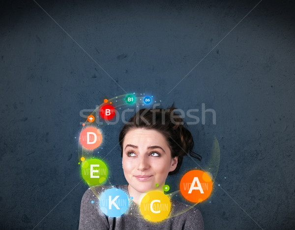 Young woman thinking with vitamins circulation around her head Stock photo © ra2studio