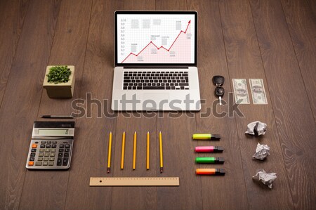 Computer desk with laptop and red arrow chart in screen Stock photo © ra2studio