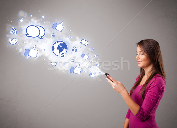 Pretty young girl holding a phone with social media icons Stock photo © ra2studio