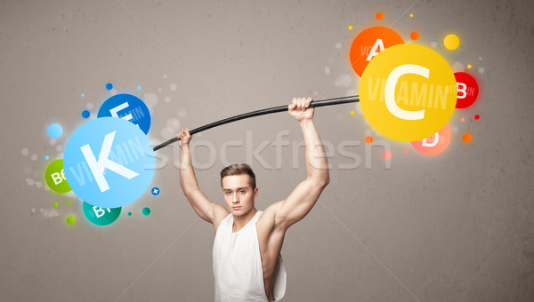 Stock photo: muscular man lifting colorful vitamin weights