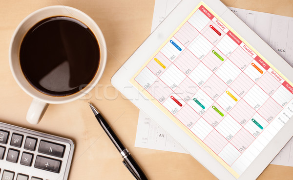 Workplace with tablet pc showing calendar and a cup of coffee on a wooden work table closeup Stock photo © ra2studio