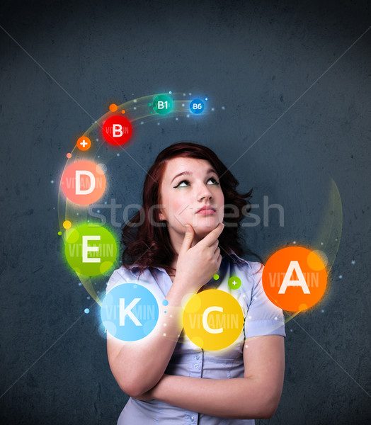 Young woman thinking with vitamins circulation around her head Stock photo © ra2studio