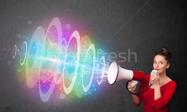 Young girl yells into a loudspeaker and colorful energy beam com Stock photo © ra2studio