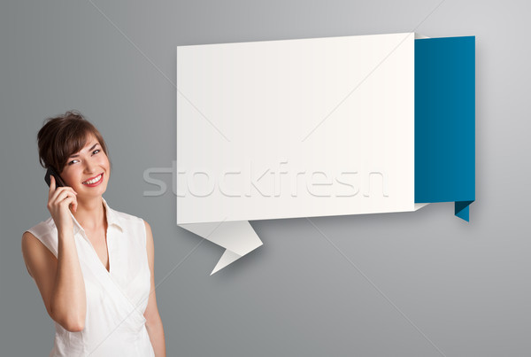 Stock photo: pretty young woman standing next to modern origami copy space and making phone call